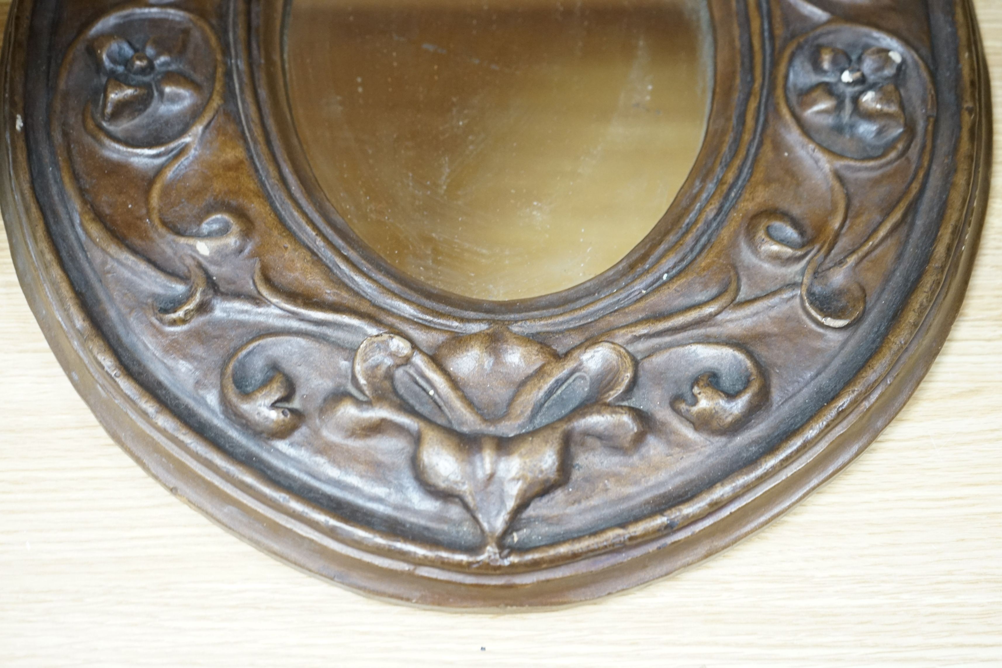 An Art Nouveau style moulded gesso oval mirror, 57cms high